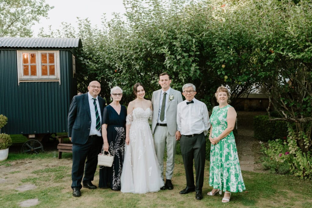 Bride and groom with family outdoors.