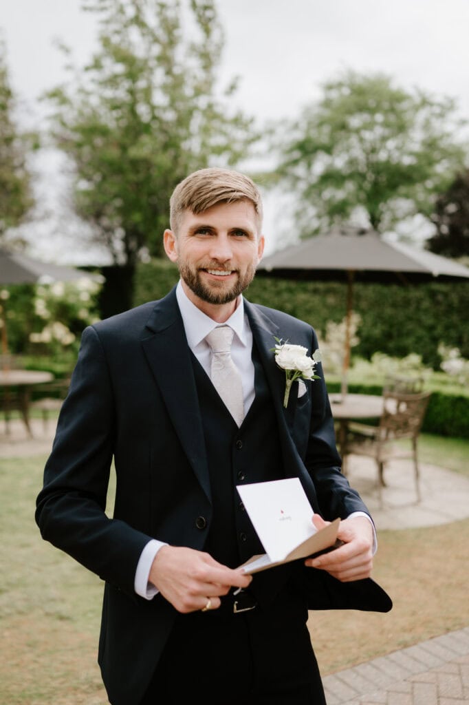 Groom reading a letter outdoors.