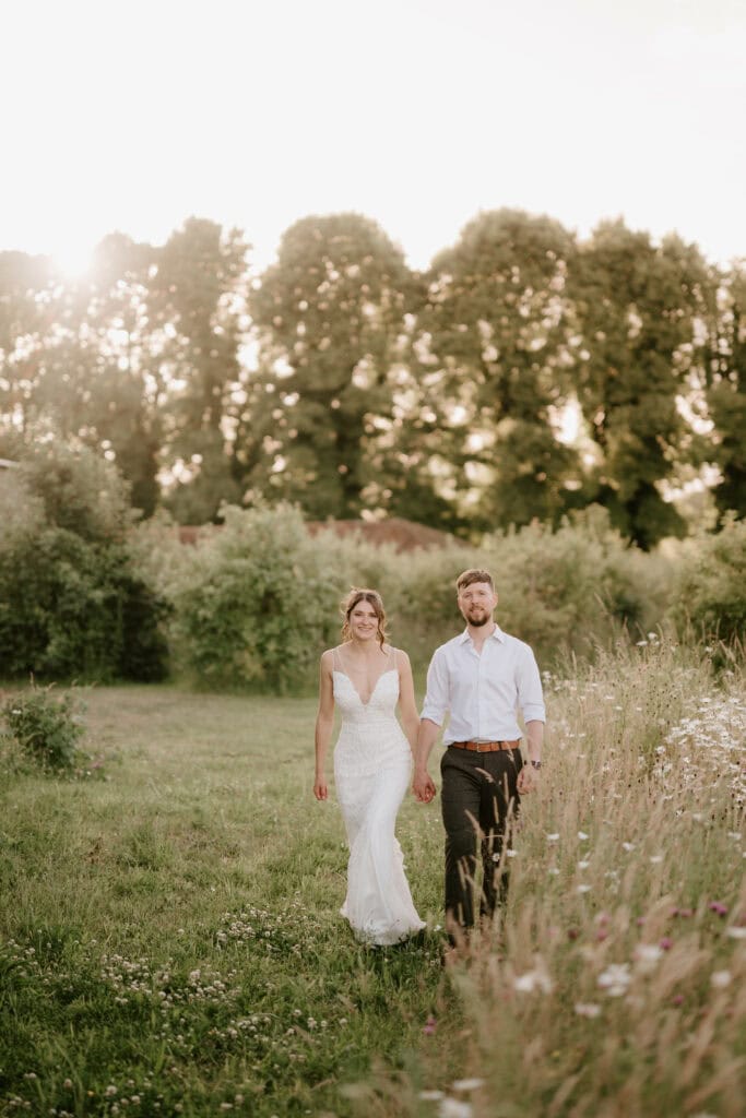 Couple walking in meadow during sunset.