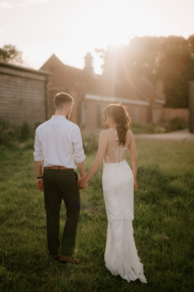 Bride and groom holding hands at sunset.