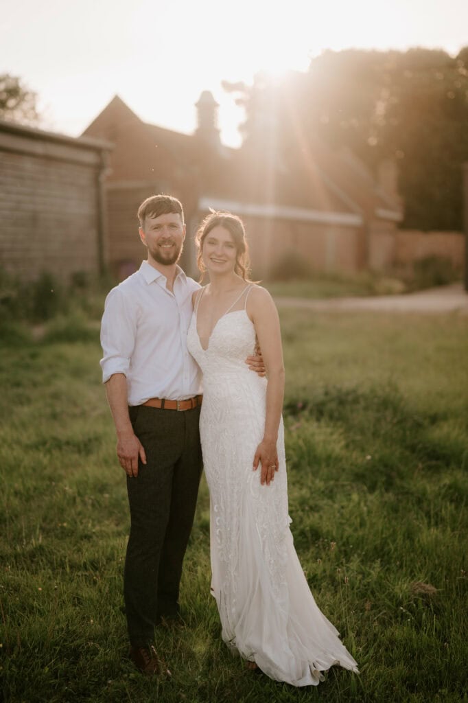 Bride and groom standing in sunlight meadow