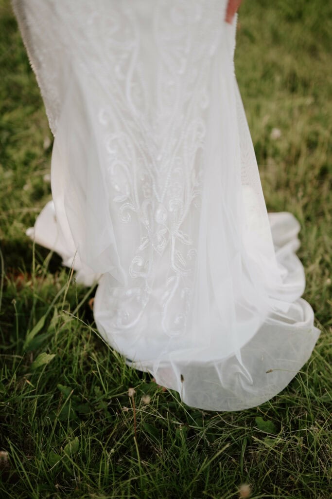 Detail of lace wedding dress on grass.