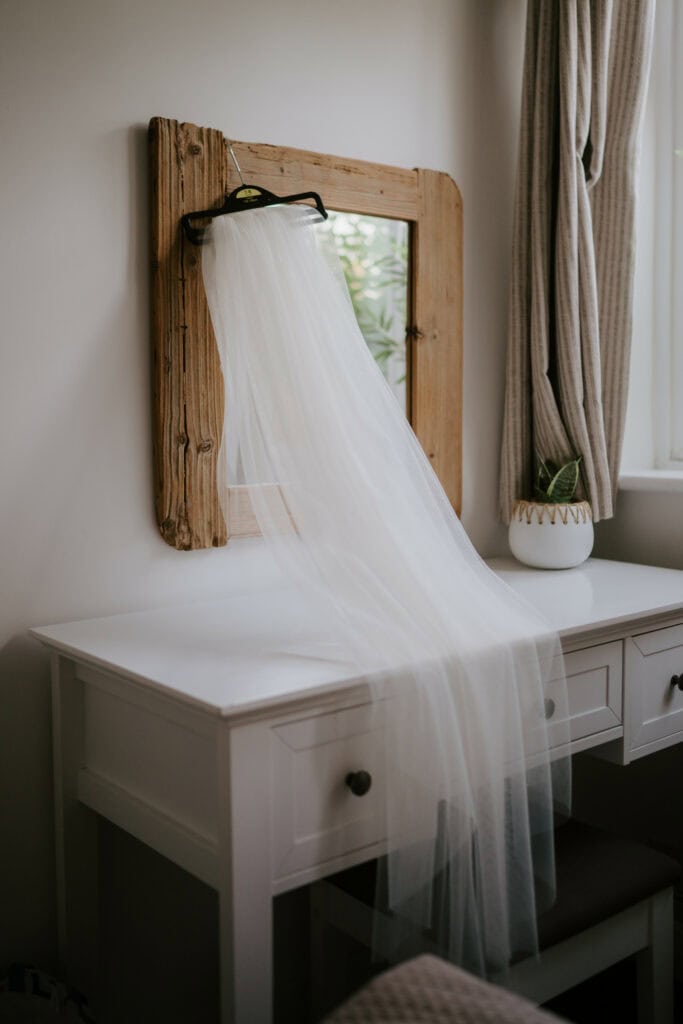 Wedding veil hanging on rustic mirror.
