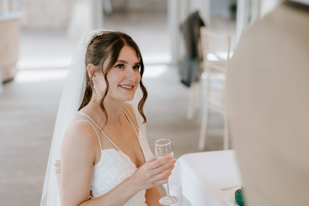 Bride smiling and holding champagne glass.