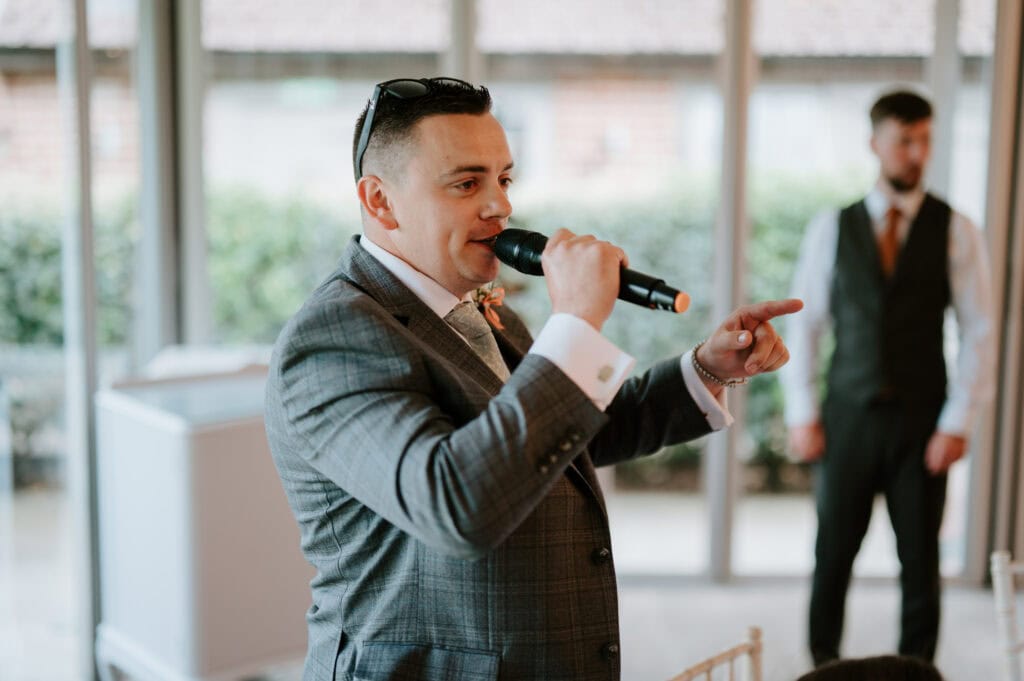 Man in suit speaking into microphone at event.