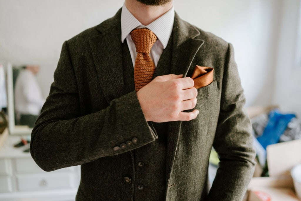 Man adjusting handkerchief in jacket pocket.