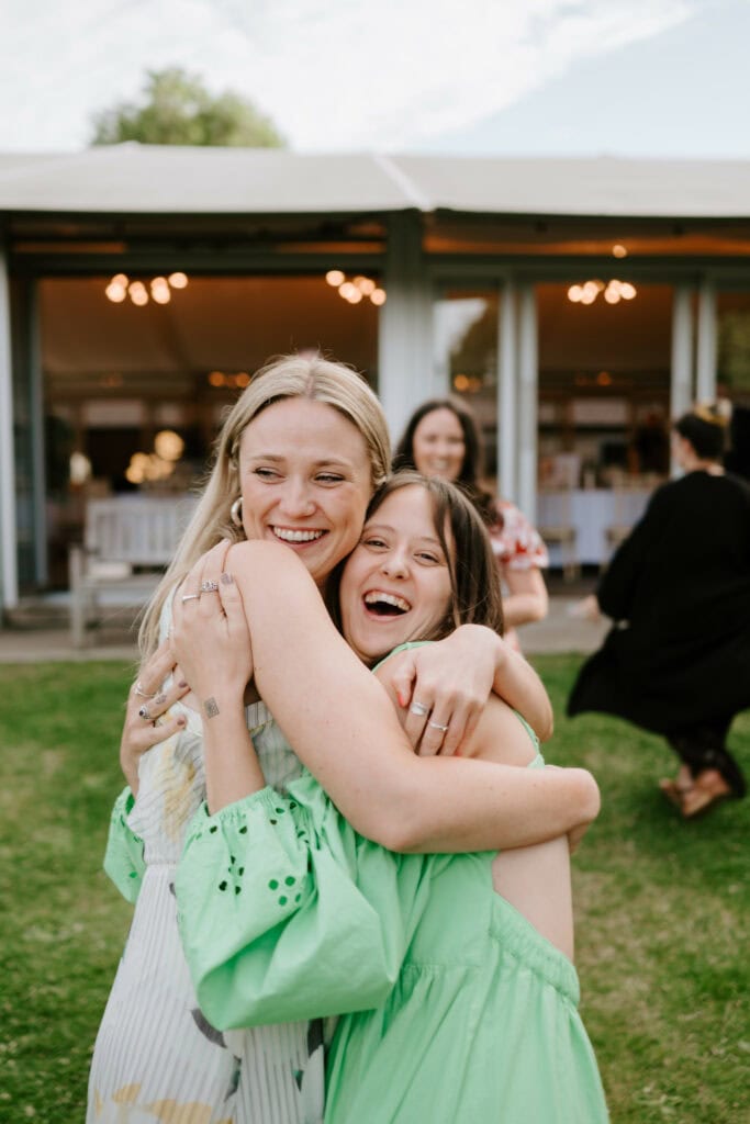 Two women hugging and smiling outdoors