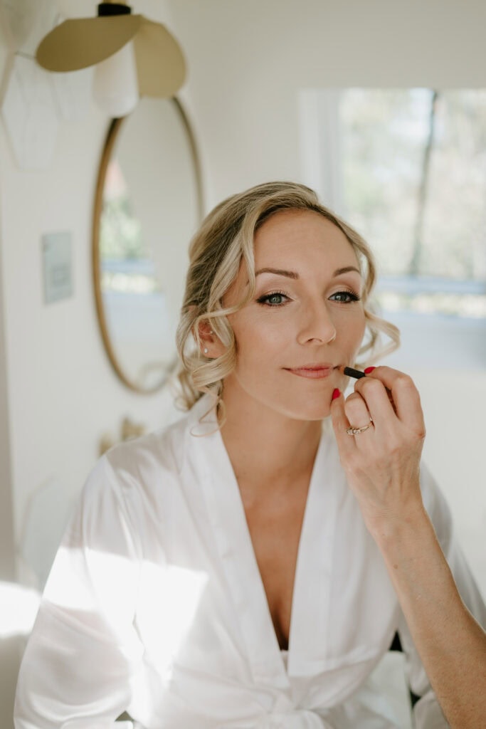 Bride applying lipstick before wedding.