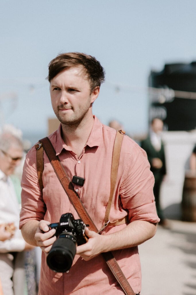 Man holding camera at outdoor event.
