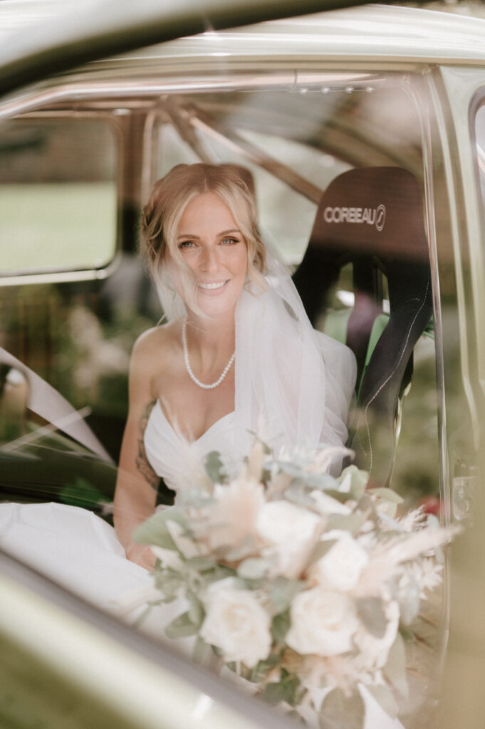 Bride sitting in car with bouquet