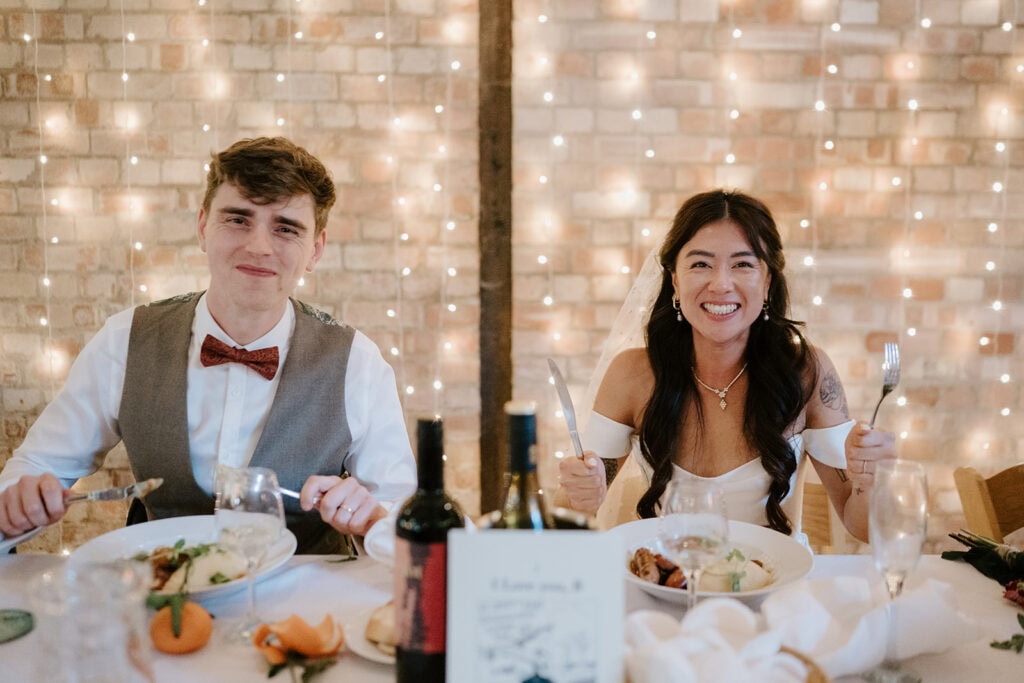 Bride and groom smiling at wedding dinner.