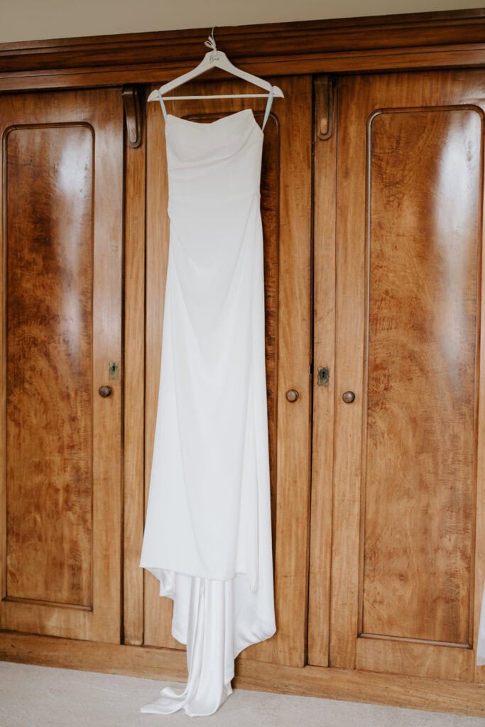 Elegant white wedding dress on wooden wardrobe.