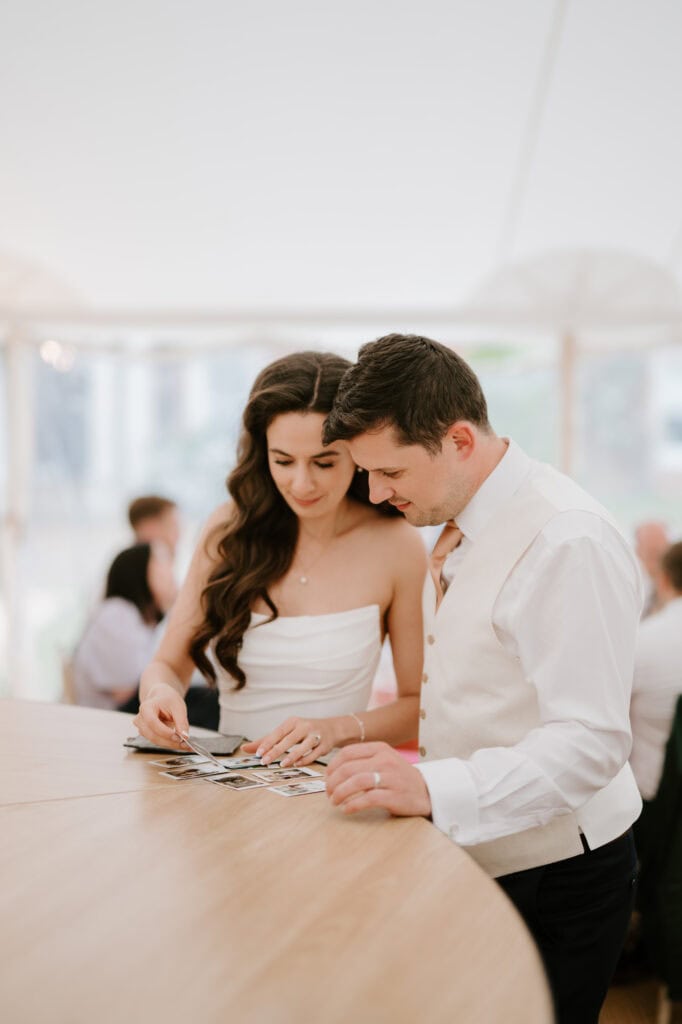Couple looking at photos on wooden table.