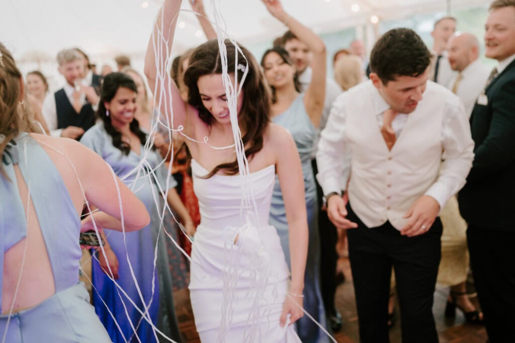 Wedding guests dancing with streamers at reception.