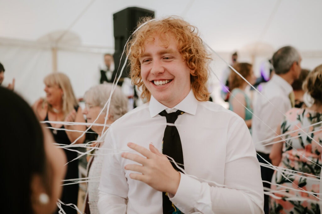 Smiling man at a lively party with streamers.