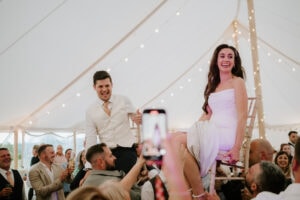 Couple lifted on chairs at celebratory event.