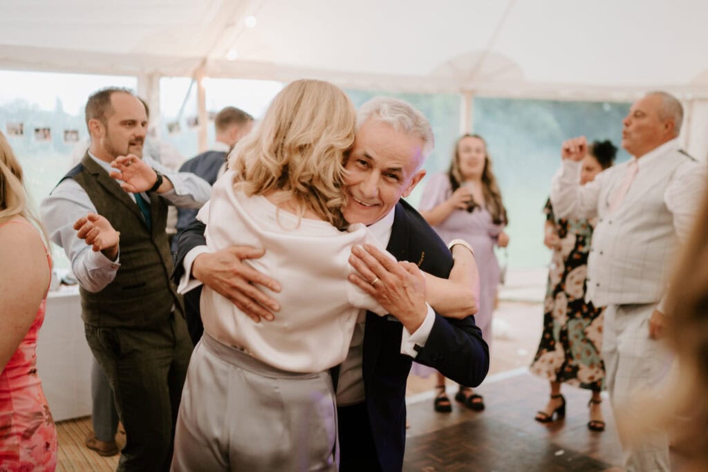 People hugging and dancing at a wedding reception.