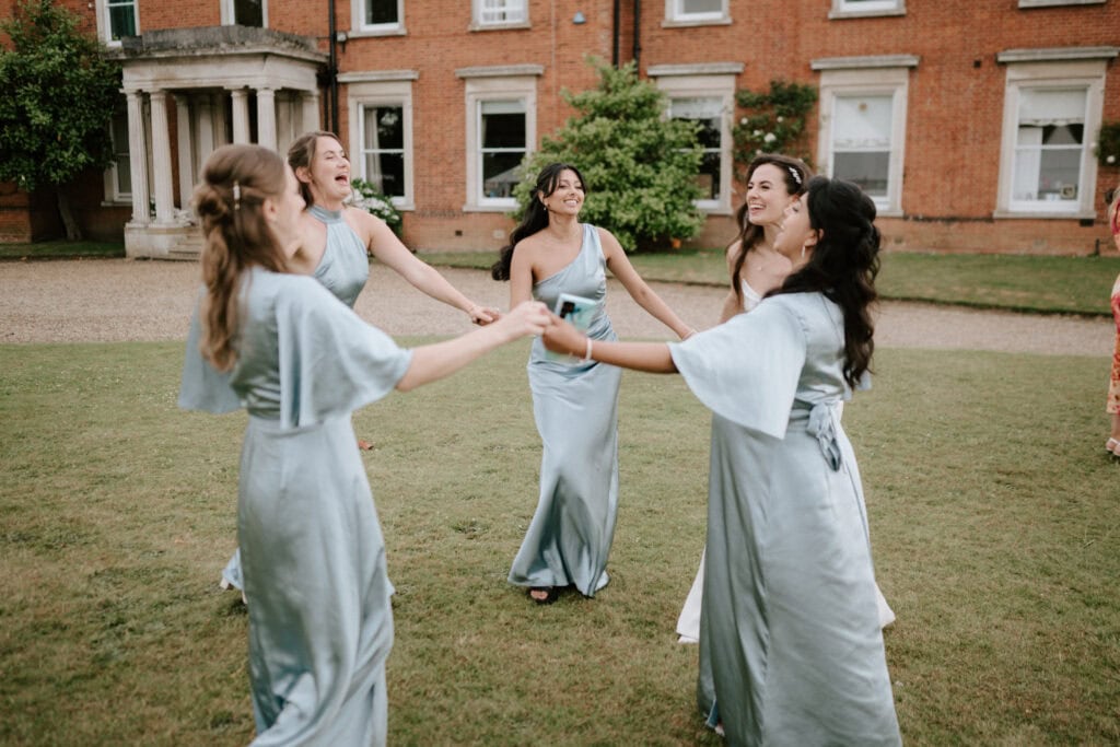 Bridesmaids dancing joyfully on lawn at wedding