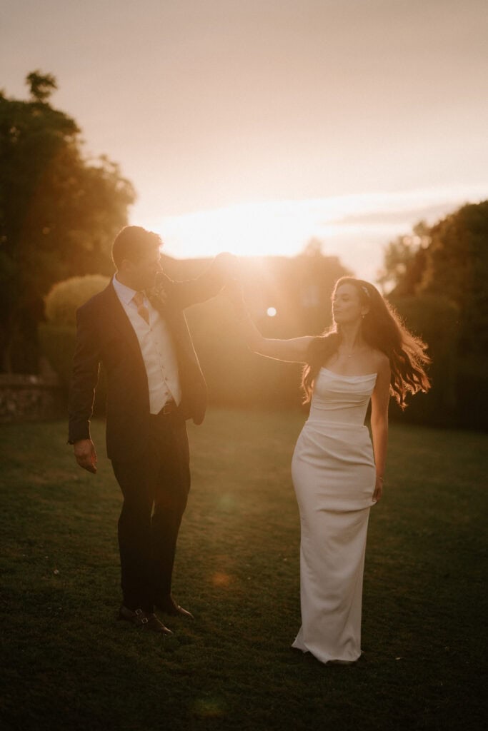 Couple dancing at sunset in elegant attire.