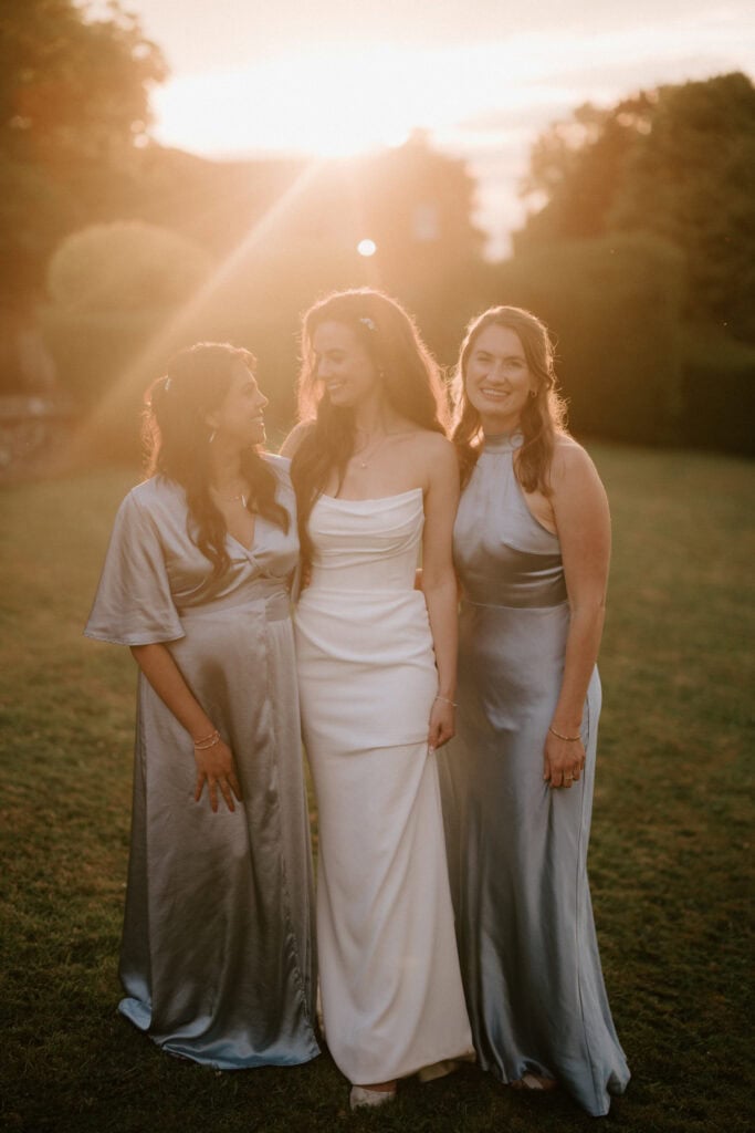 Three women in elegant dresses at sunset.