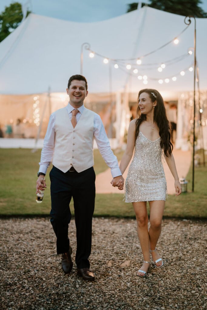 Happy couple walking hand in hand at wedding.