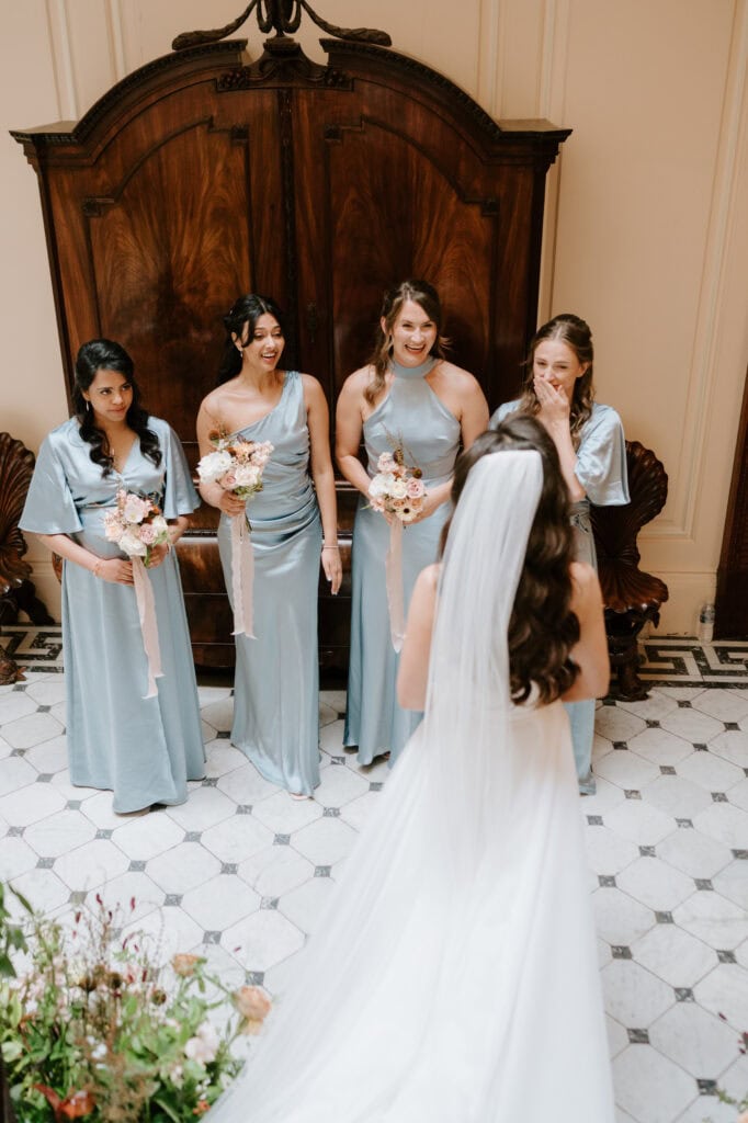 Bride and bridesmaids in blue dresses, wooden wardrobe background.