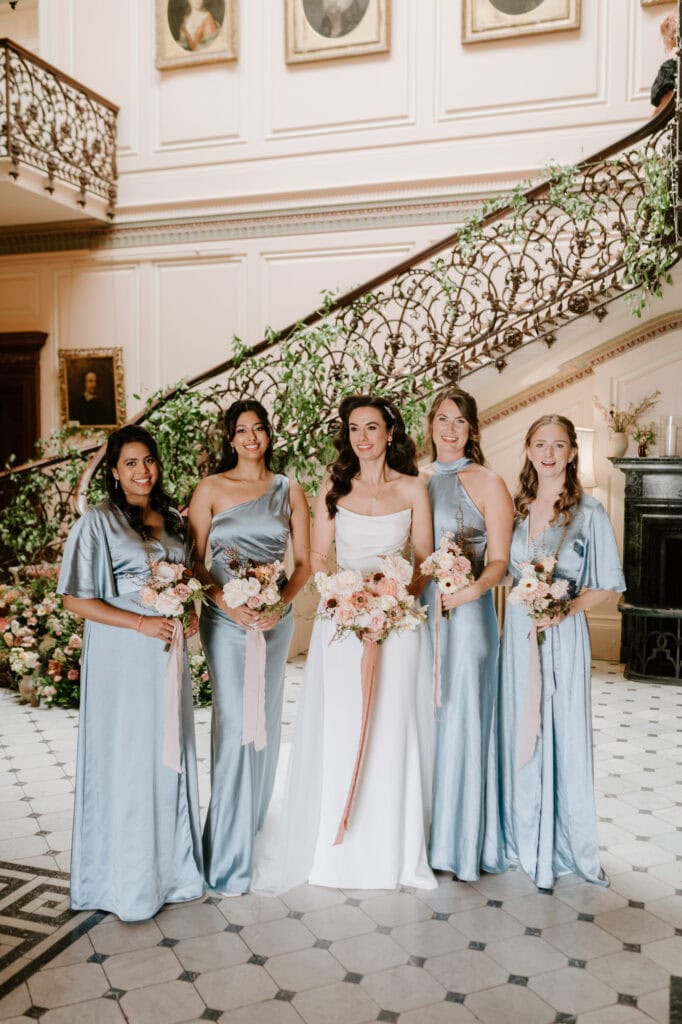 Bride with bridesmaids in elegant indoor setting.