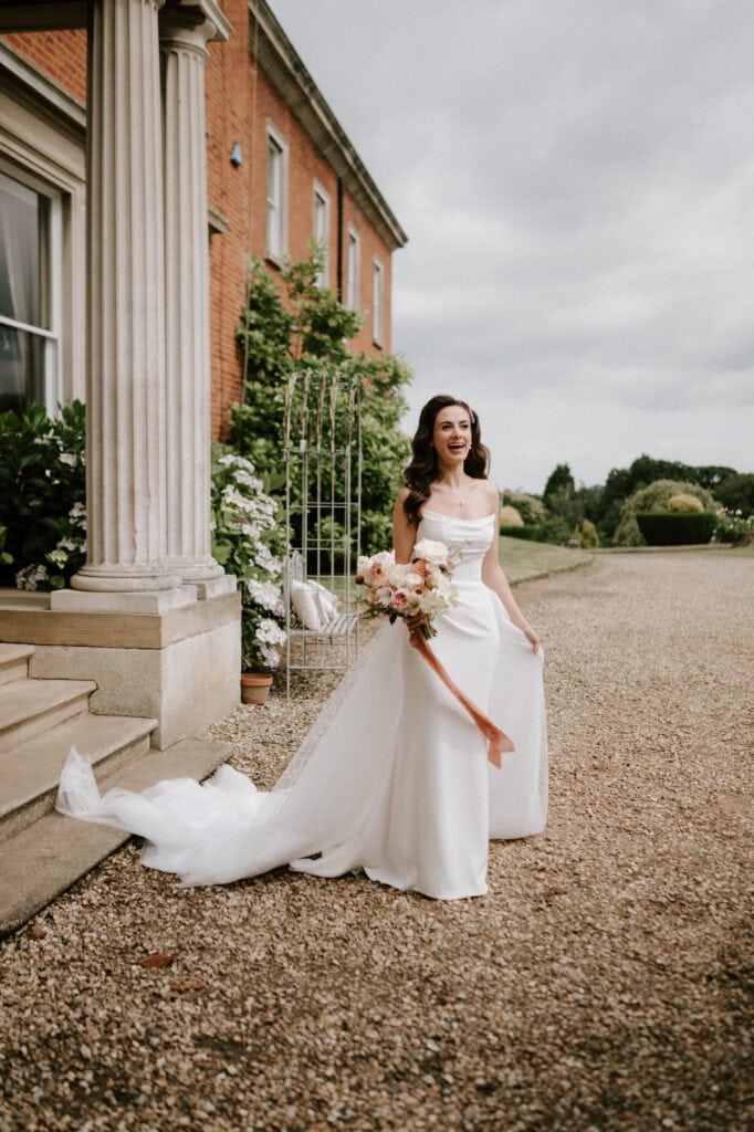 Bride in white dress holding flower bouquet outdoors