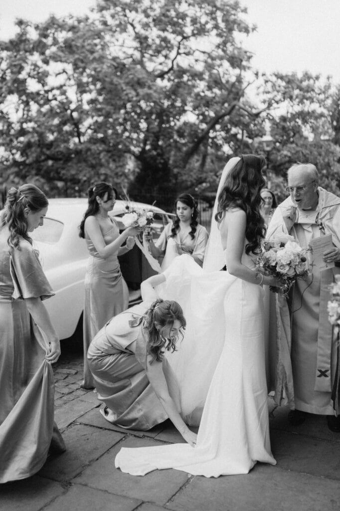 Bridesmaids adjust bride's dress before ceremony.