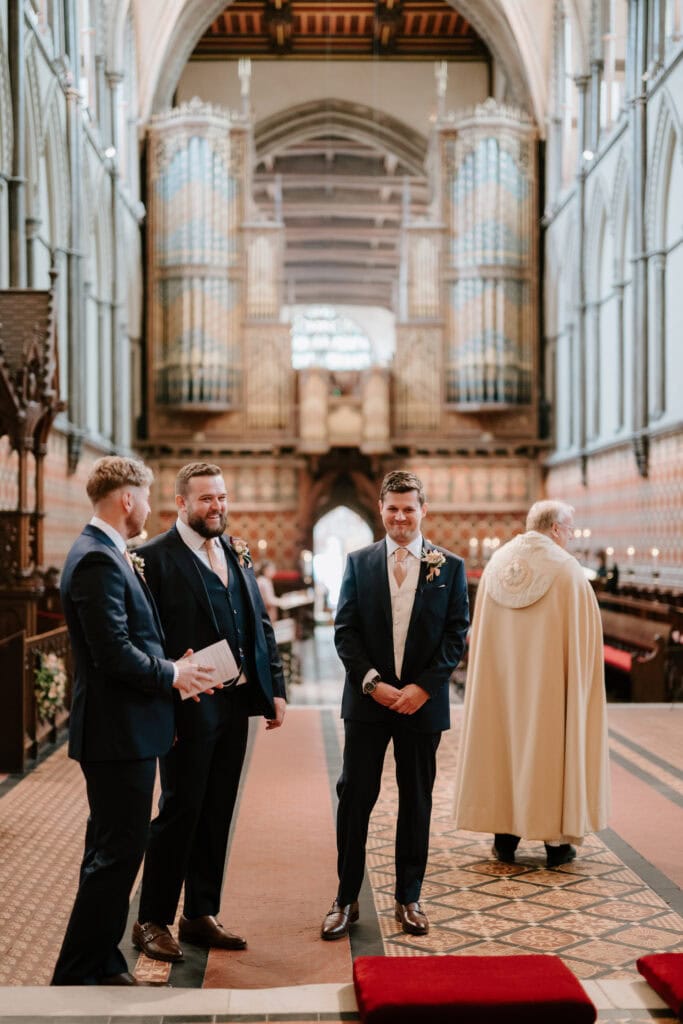 Groom and groomsmen in historic church, wedding ceremony.