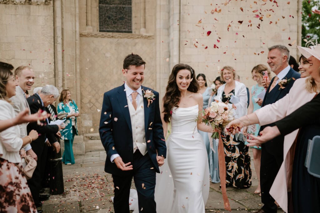 Bride and groom exit wedding with confetti celebration.