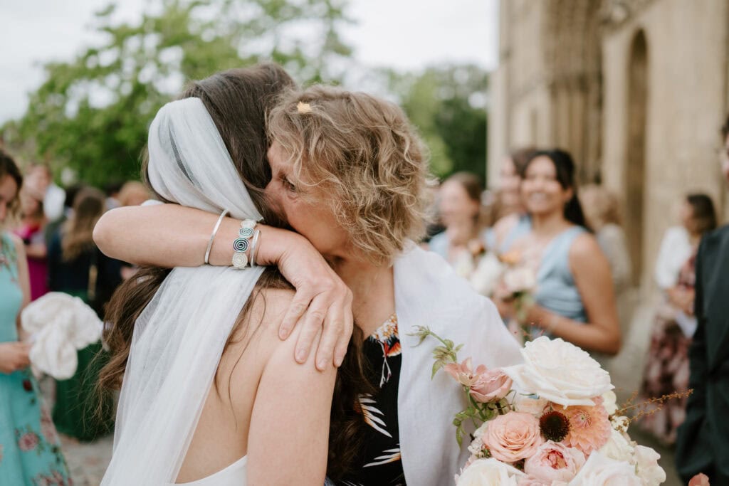 Wedding guests hugging with a flower bouquet.