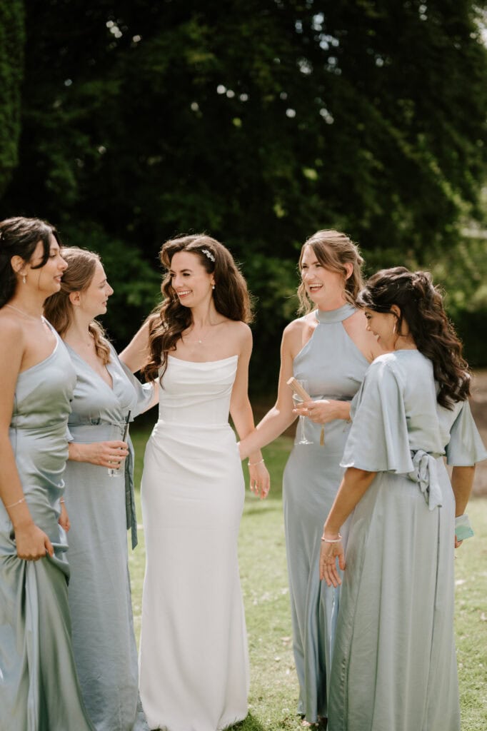 Bride with bridesmaids in light blue dresses, outdoors.