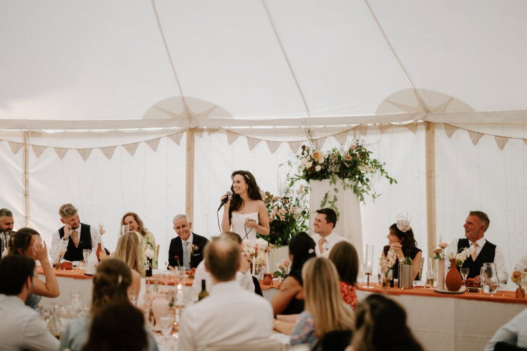 Wedding reception speech under a decorated tent.