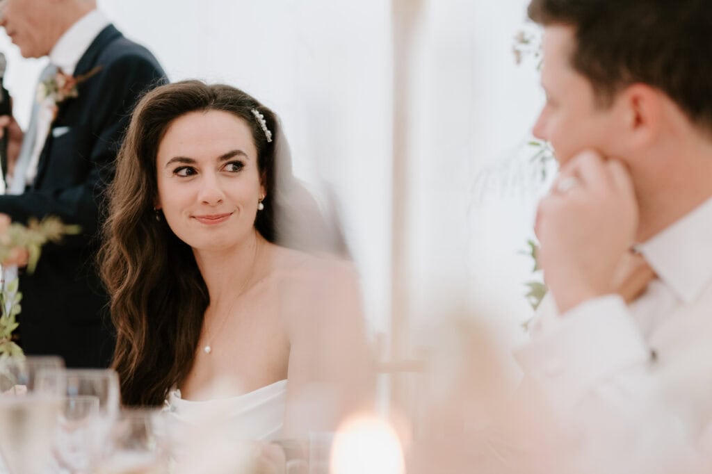 Bride smiling at wedding reception, elegant atmosphere.