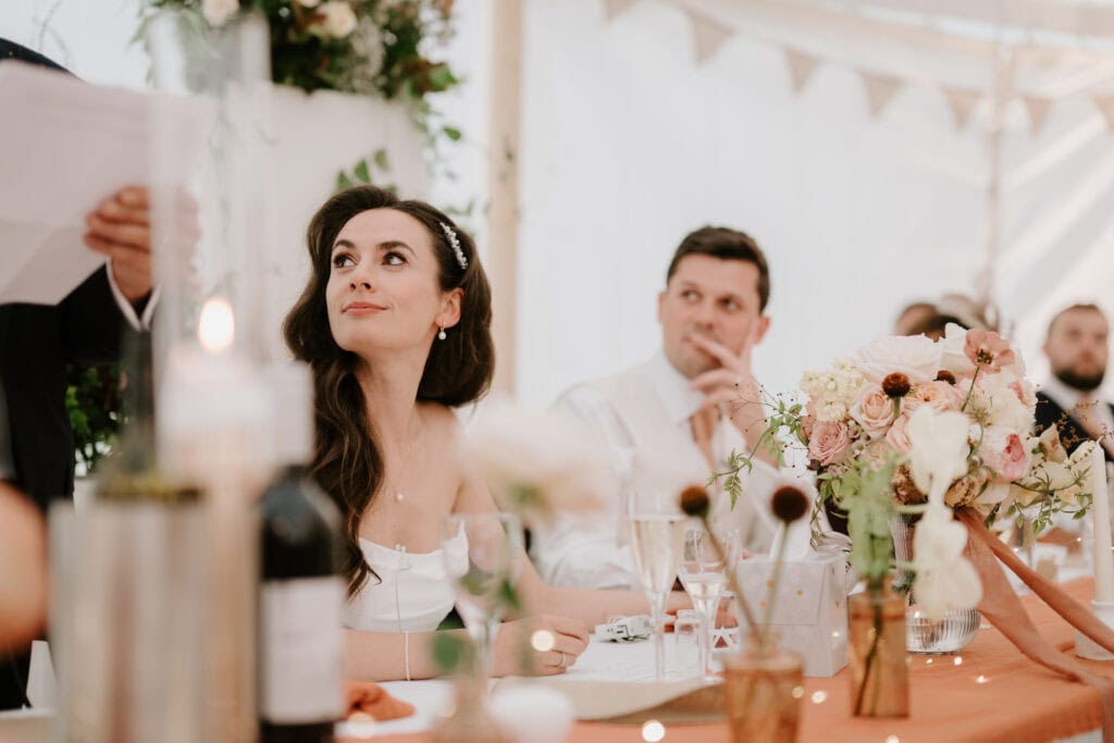 Bride and guests listening during wedding speeches.