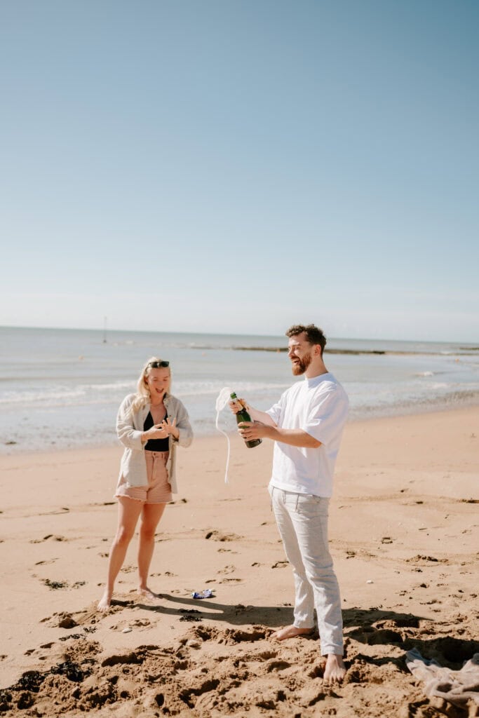 Couple celebrating on beach with champagne.