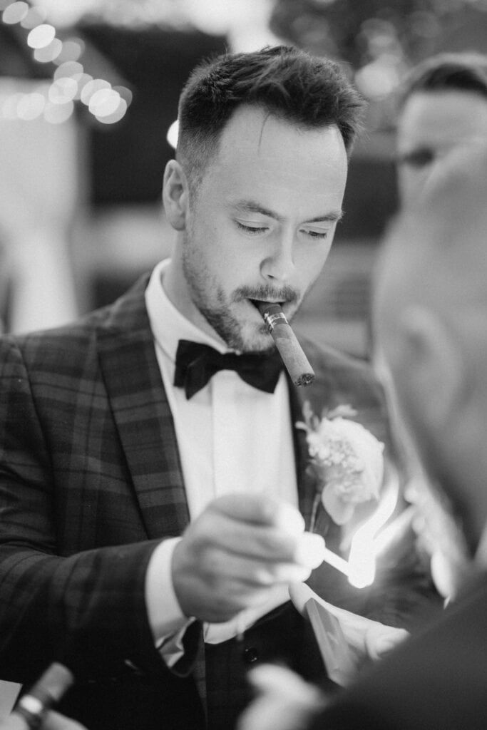 Man in suit lighting cigar.
