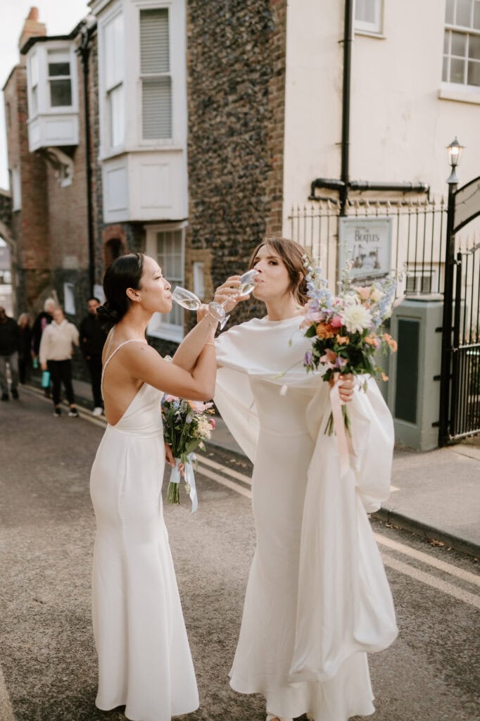 Brides toasting with champagne on street.