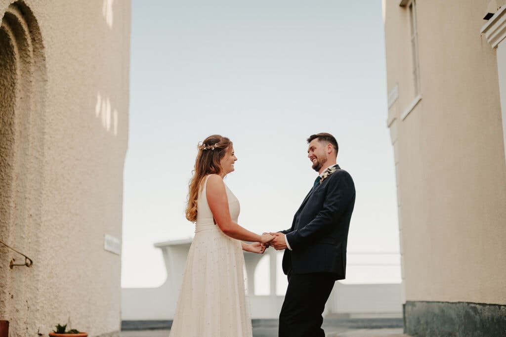 Bride and groom smiling at each other outdoors