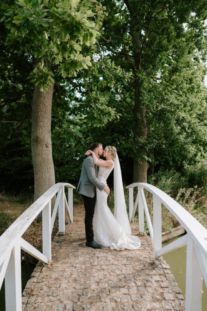 Bride and groom kissing on a bridge.