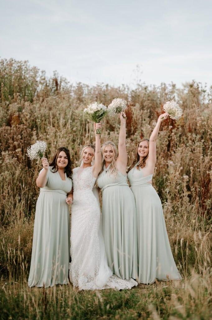 Bride with bridesmaids holding flowers outdoors.