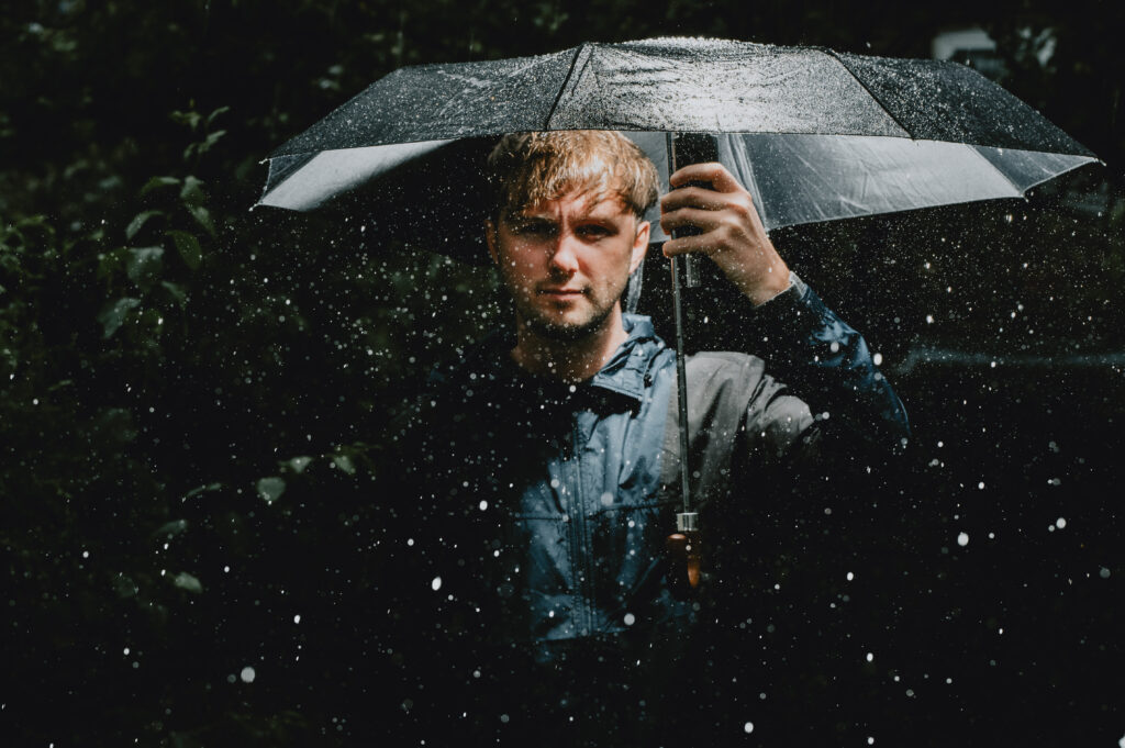 Person under umbrella in rainy garden