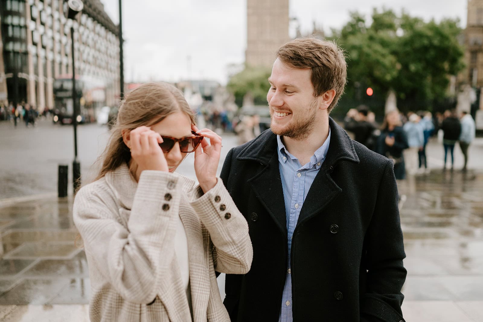 Couple smiling in urban setting with sunglasses.