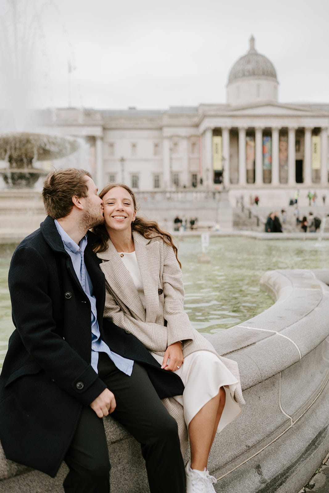 Couple smiling by fountain at historic building