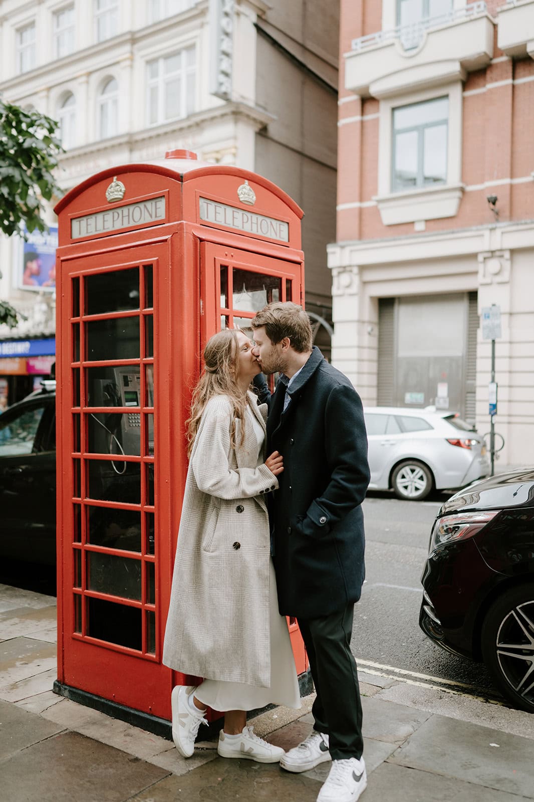Couple kissing by a red London telephone box.