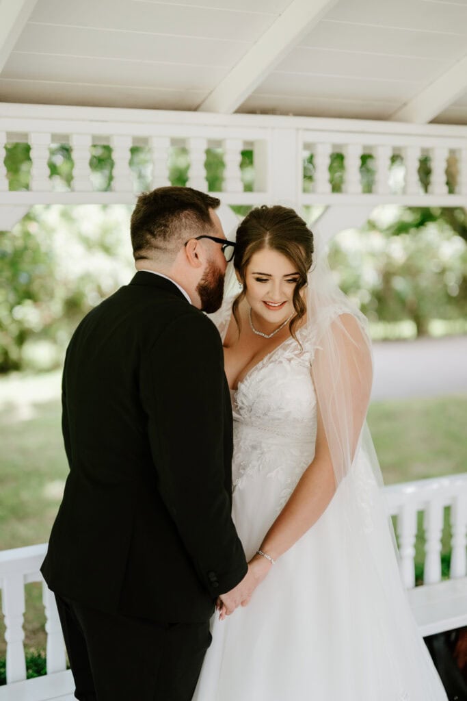 Bride and groom sharing a moment under gazebo.
