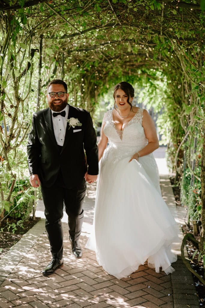 Bride and groom walking under leafy archway