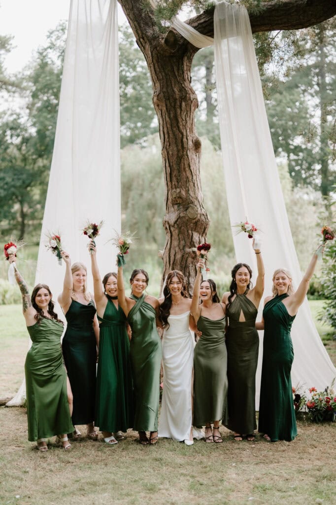 Bridesmaids in green dresses celebrating outdoors.