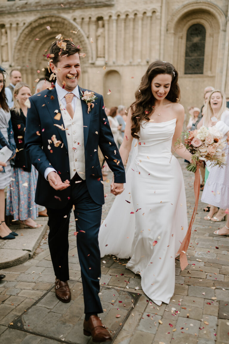 Newlyweds walking under shower of confetti.
